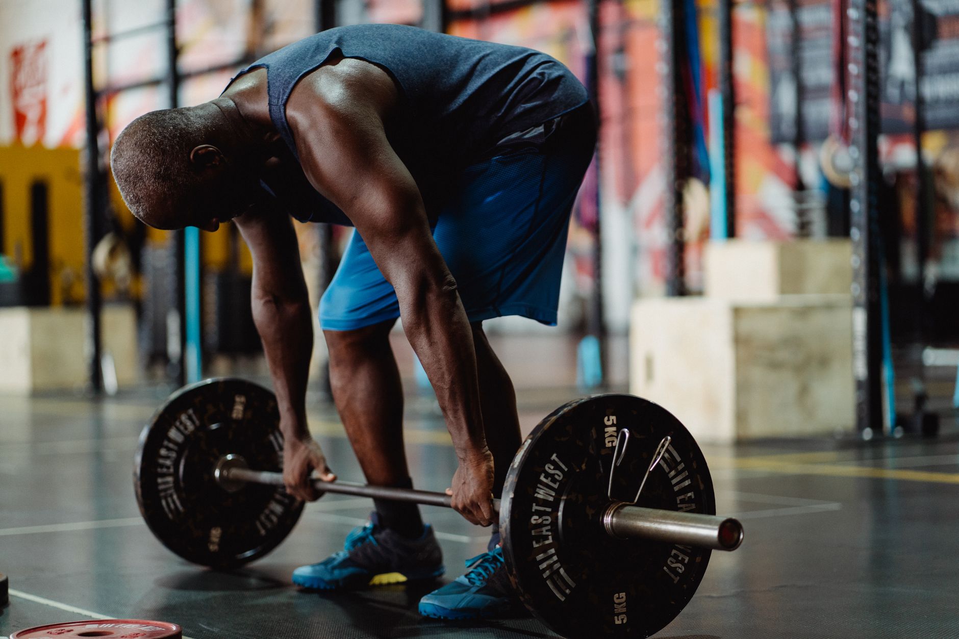 Athlete beginning a barbell deadlift in a working gym.